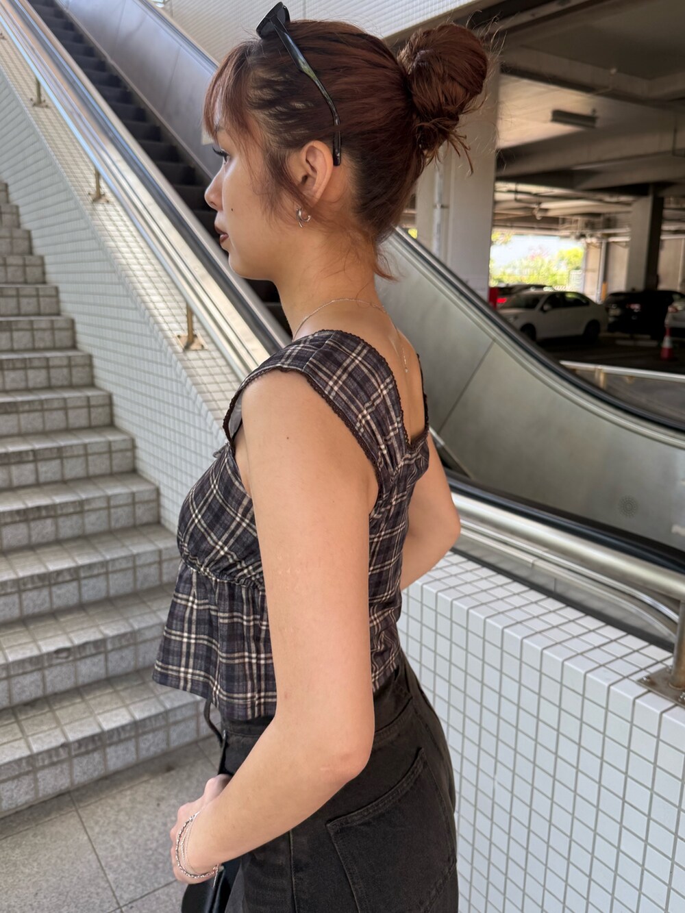 ブラウン系のタンクトップ、ブラック系のハンドバッグ、ブラック系のデニムパンツを着用したレディースの夏コーディネートの5枚目の写真