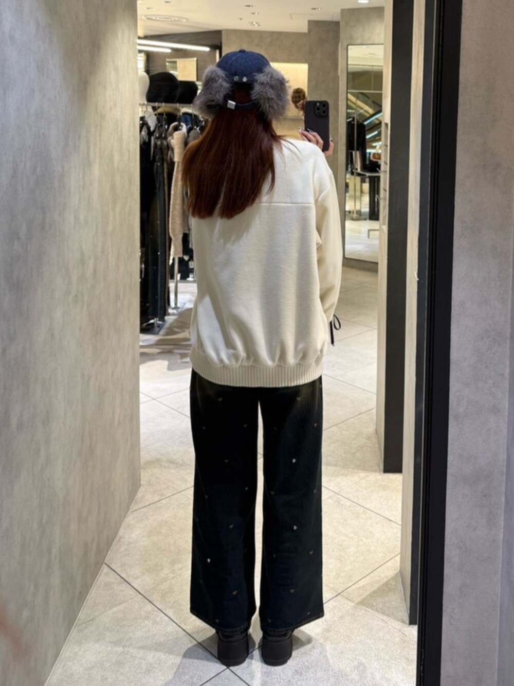 ブラック系のブーツ、ブルー系のデニムパンツ、ホワイト系のブルゾンを着用したレディースの秋コーディネートの3枚目の写真