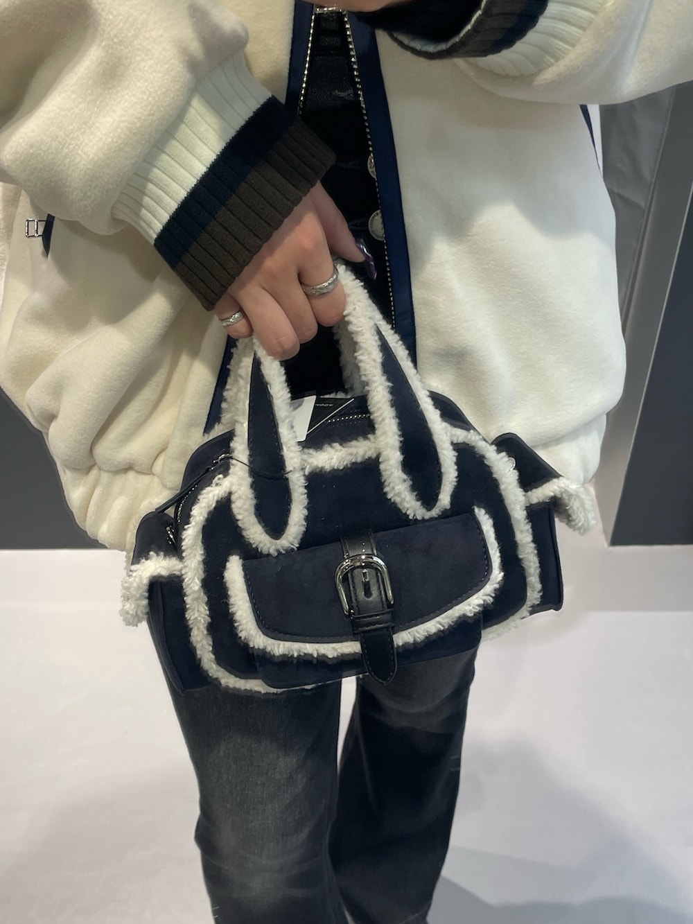 ホワイト系のブルゾン、ブルー系のハンドバッグ、ブラック系のデニムパンツを着用したレディースの秋コーディネートの6枚目の写真