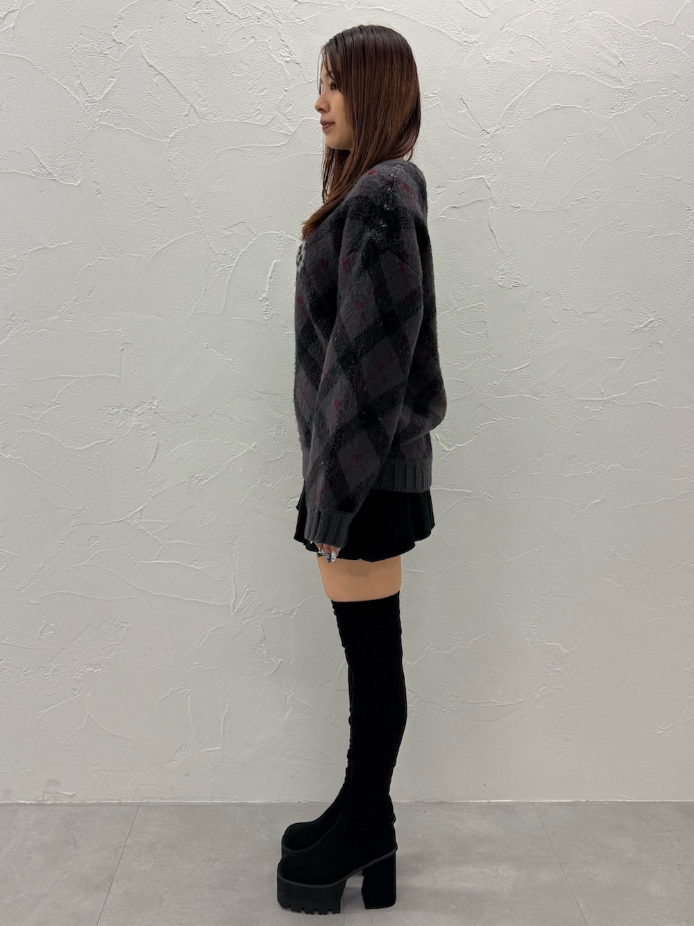 ブラック系のブーツ、グレー系のニット/セーター、ブラック系のスカートを着用したレディースの冬コーディネートの2枚目の写真