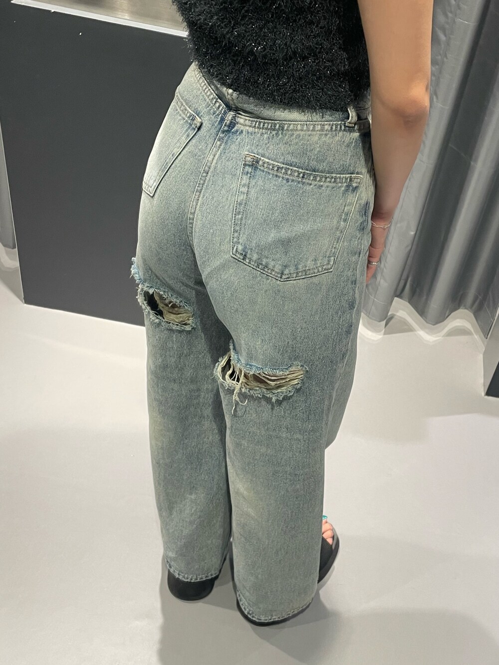 グレー系のタンクトップ、ブルー系のデニムパンツ、ブラック系のサンダルを着用したレディースの夏コーディネートの8枚目の写真