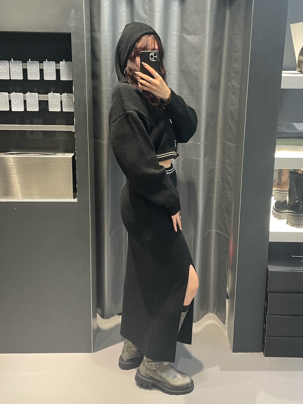 ブラック系のニット/セーター、ブラック系のスカート、シルバー系のブーツを着用したレディースの冬コーディネートの2枚目の写真