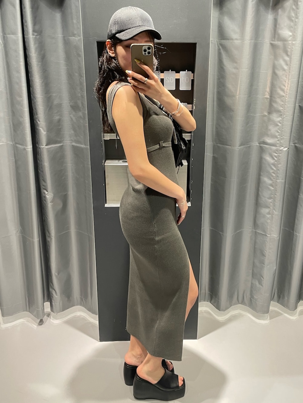 ブラック系のハンドバッグ、グレー系のワンピース、ブラック系のサンダルを着用したレディースの春コーディネートの2枚目の写真