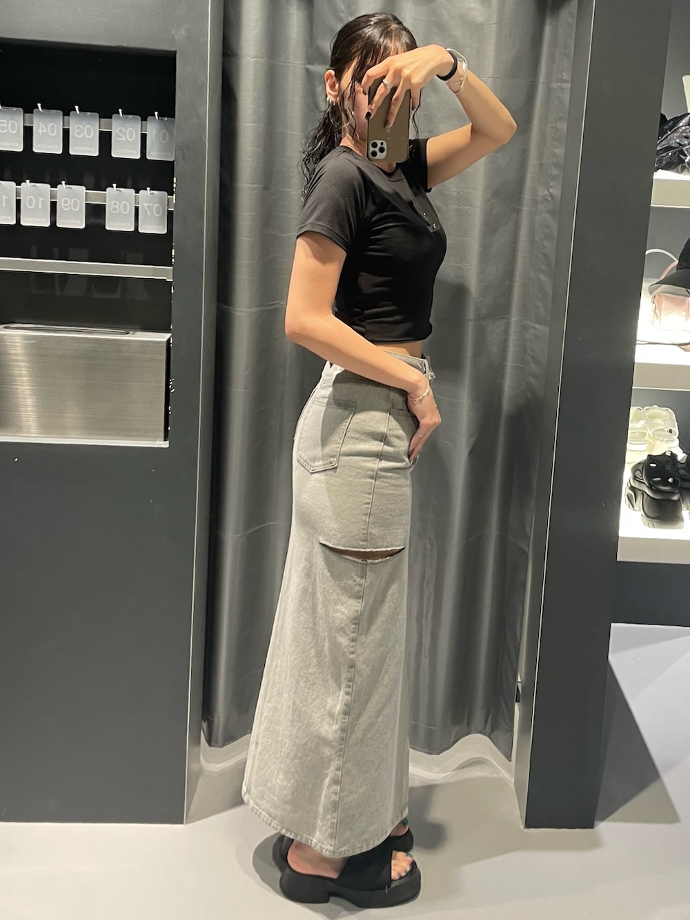 ブラック系のTシャツ/カットソー、グレー系のデニムスカート、ブラック系のサンダルを着用したレディースの夏コーディネートの2枚目の写真