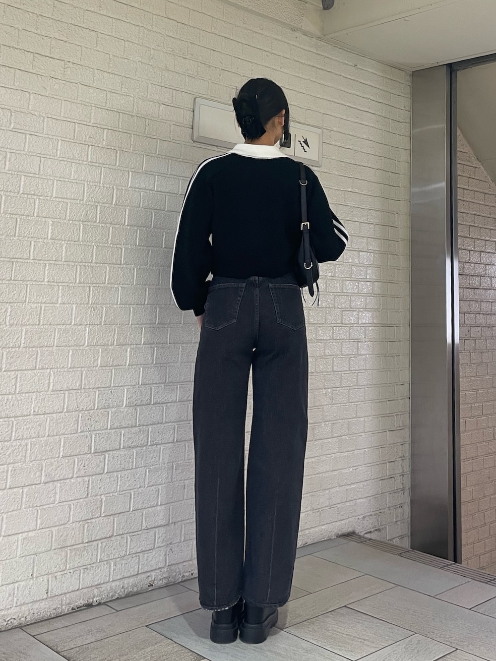 ブラック系のニット/セーター、ブラック系のハンドバッグ、ブラック系のデニムパンツを着用したレディースの冬コーディネートの3枚目の写真