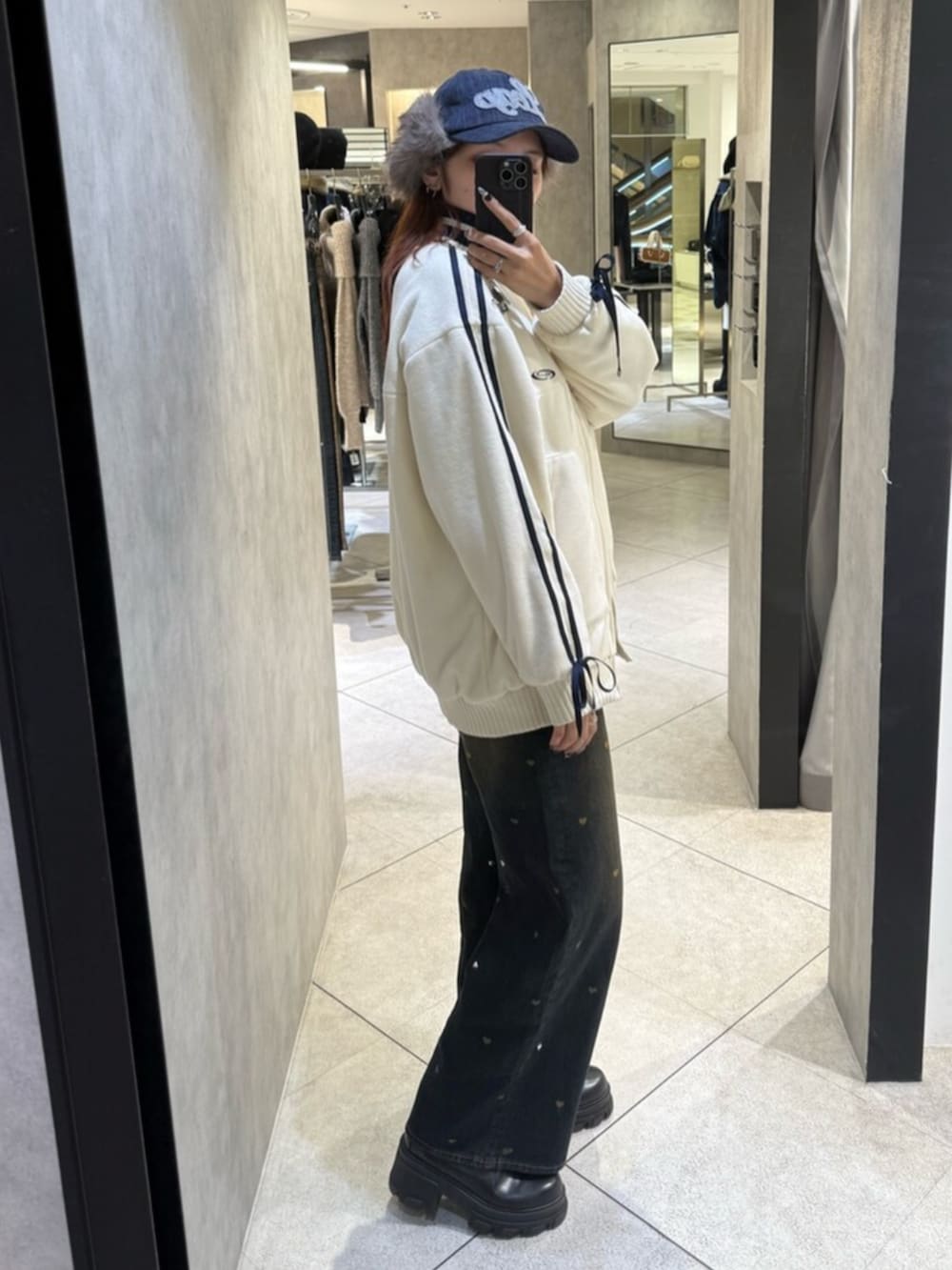 ブラック系のブーツ、ブルー系のデニムパンツ、ホワイト系のブルゾンを着用したレディースの秋コーディネートの2枚目の写真