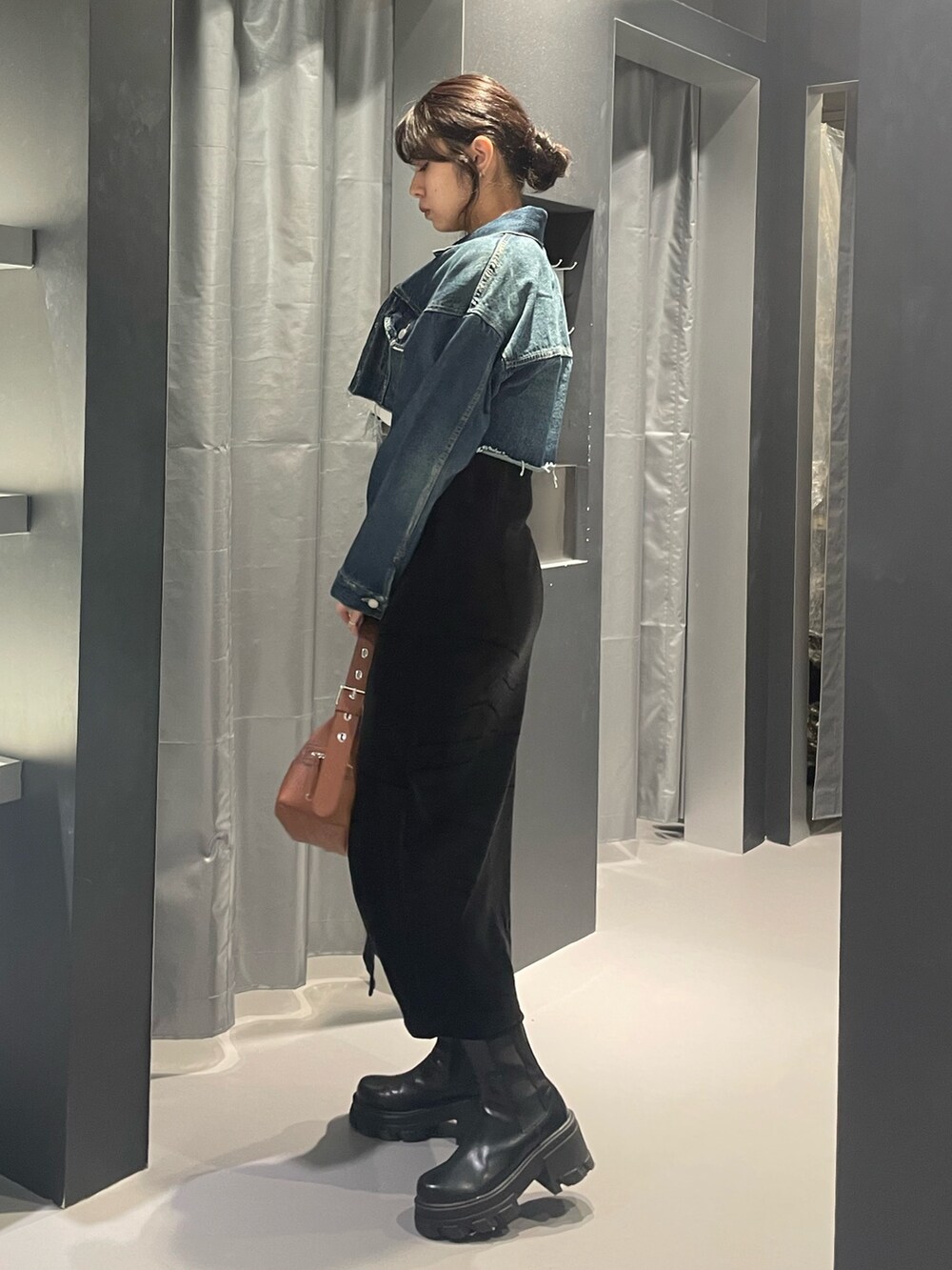 ブルー系のデニムジャケット、ブラック系のワンピース、イエロー系のハンドバッグを着用したレディースの秋コーディネートの2枚目の写真