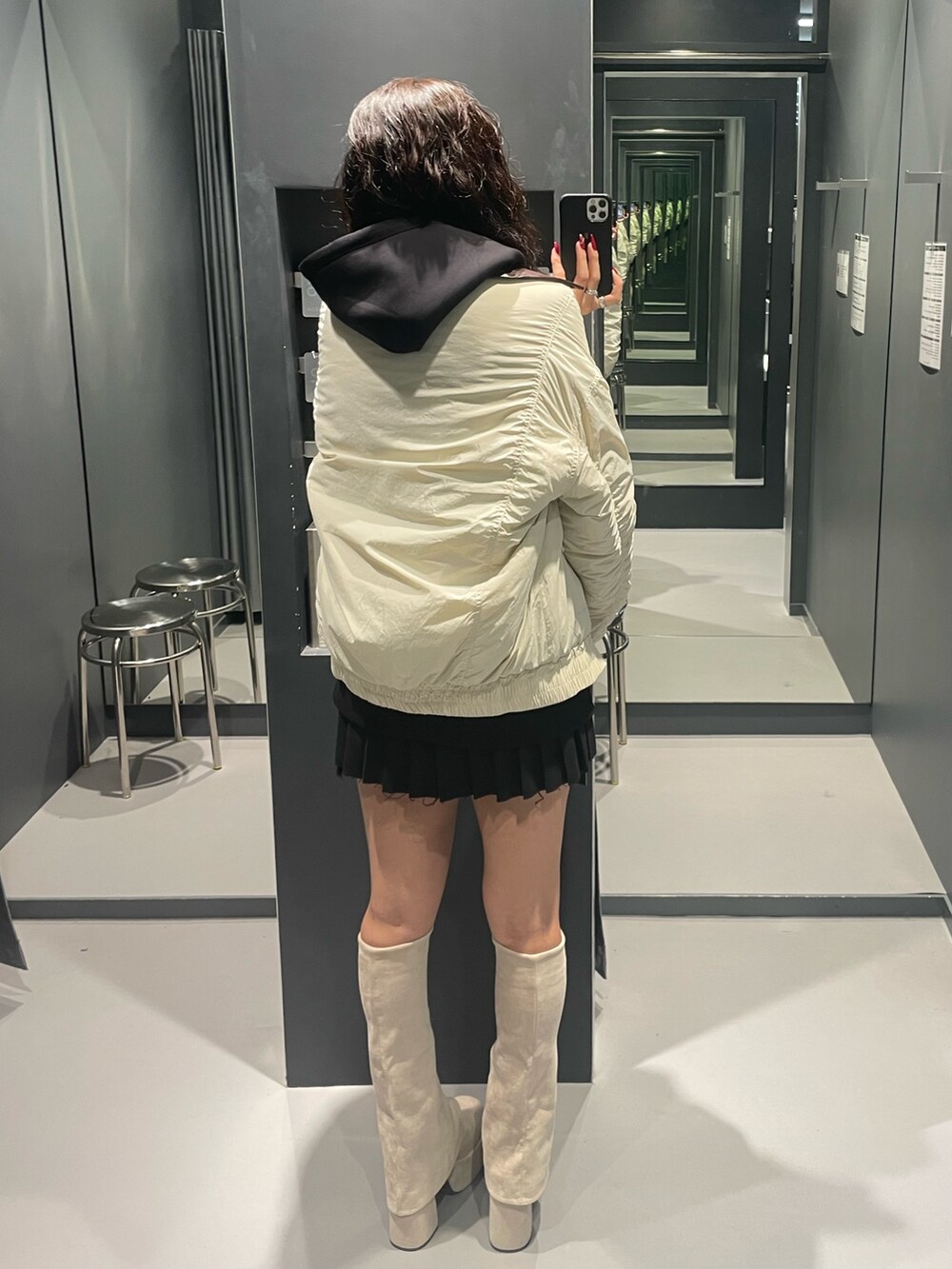 ブラック系のパーカー、ホワイト系のブルゾン、ブラック系のスカートを着用したレディースの秋コーディネートの3枚目の写真