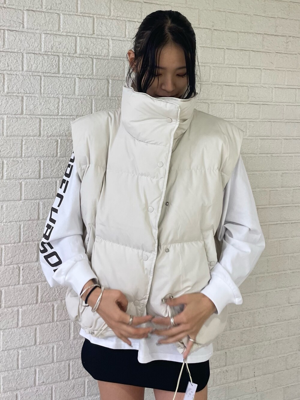 ホワイト系のTシャツ/カットソー、ホワイト系のダウンベスト、ブラック系のスカートを着用したレディースの秋コーディネートの5枚目の写真