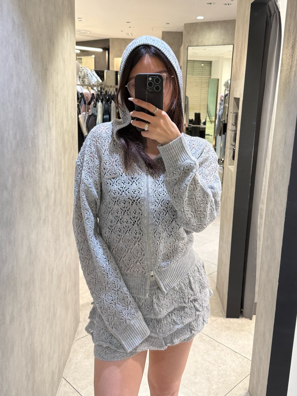 グレー系のパーカー、グレー系のスカート、ブラック系のサンダルを着用したレディースの春コーディネートの4枚目の写真