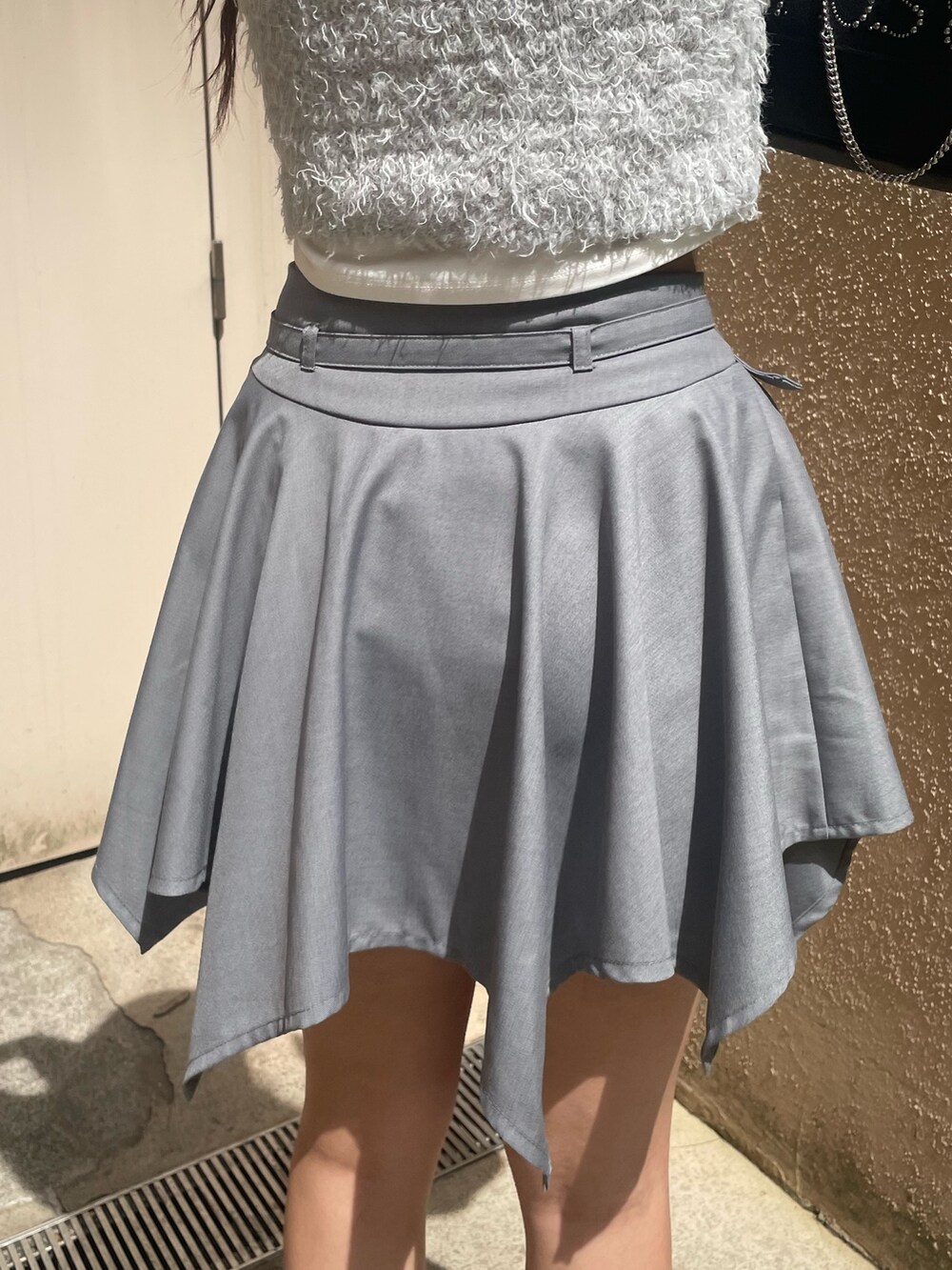 ホワイト系のTシャツ/カットソー、グレー系のニット/セーター、グレー系のスカートを着用したレディースの春コーディネートの7枚目の写真