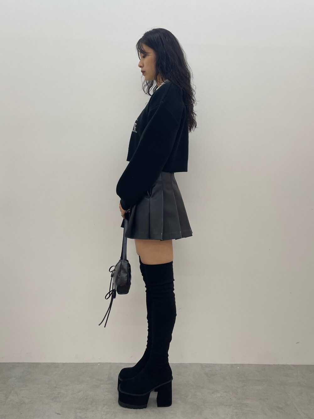 ブラック系のニット/セーター、グレー系のスカート、ブラック系のショルダーバッグを着用したレディースの夏コーディネートの2枚目の写真
