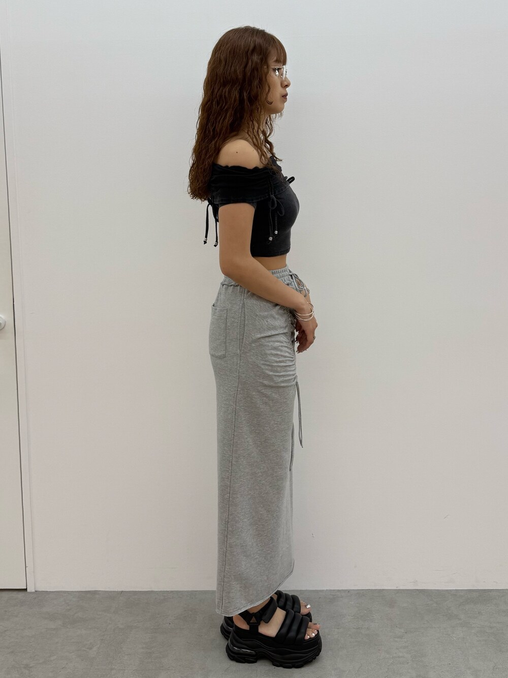 ブラック系のTシャツ/カットソー、グレー系のスカート、ブラック系のサンダルを着用したレディースの夏コーディネートの2枚目の写真