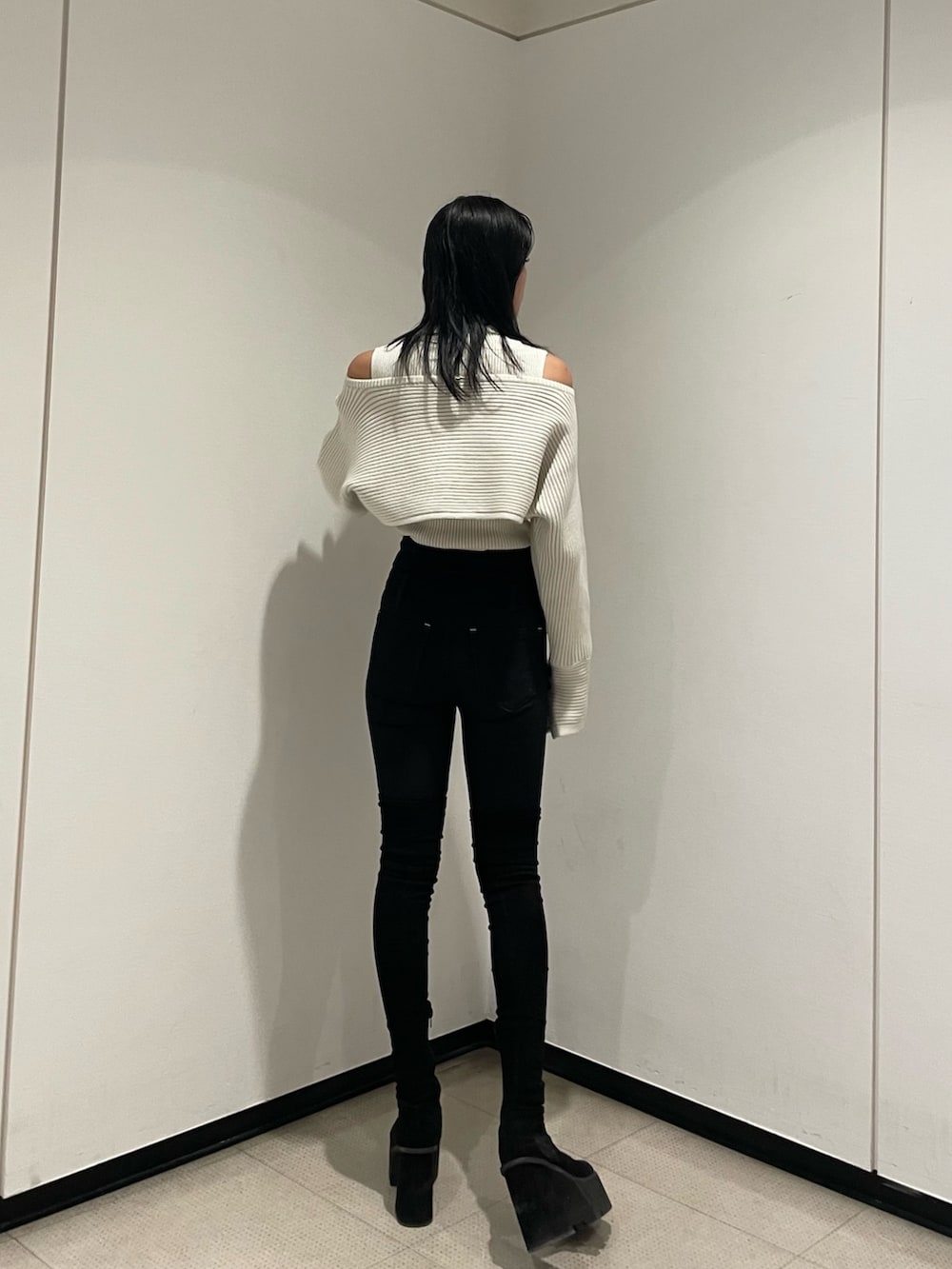 ホワイト系のニット/セーター、ブラック系のデニムパンツ、ブラック系のブーツを着用したレディースの秋コーディネートの8枚目の写真