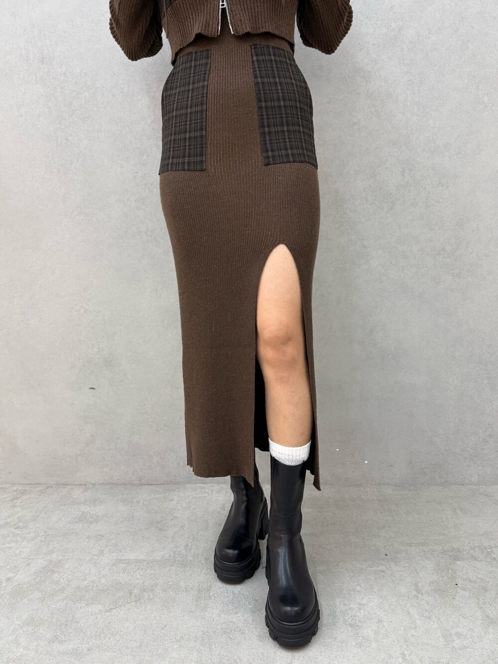 グリーン系のニット/セーター、グリーン系のワンピース、ブラック系のブーツを着用したレディースの秋コーディネートの5枚目の写真