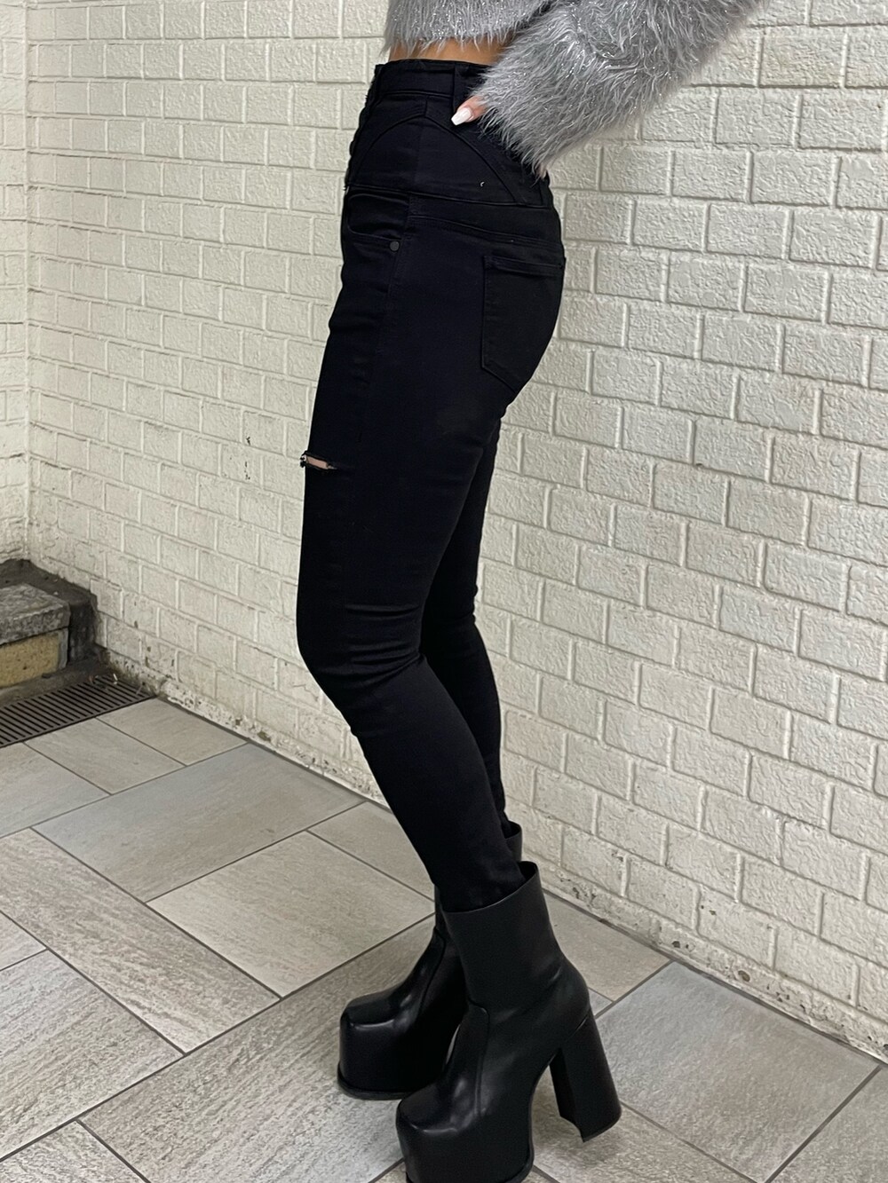 グレー系のニット/セーター、ブラック系のデニムパンツ、ブラック系のブーツを着用したレディースの冬コーディネートの8枚目の写真