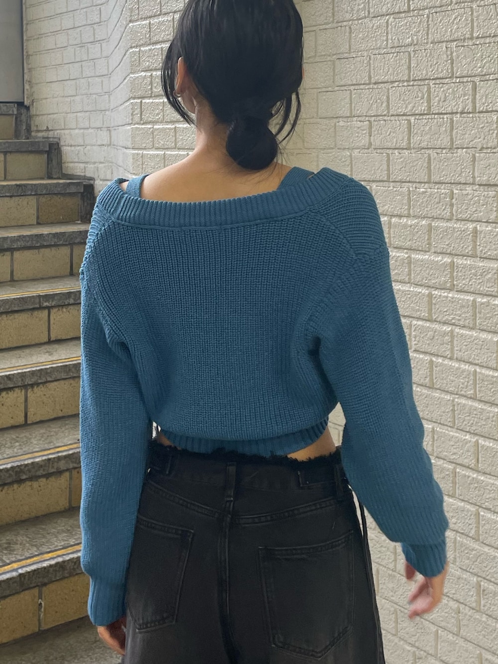 ブルー系のニット/セーター、ブラック系のデニムパンツ、ブラック系のブーツを着用したレディースの春コーディネートの6枚目の写真