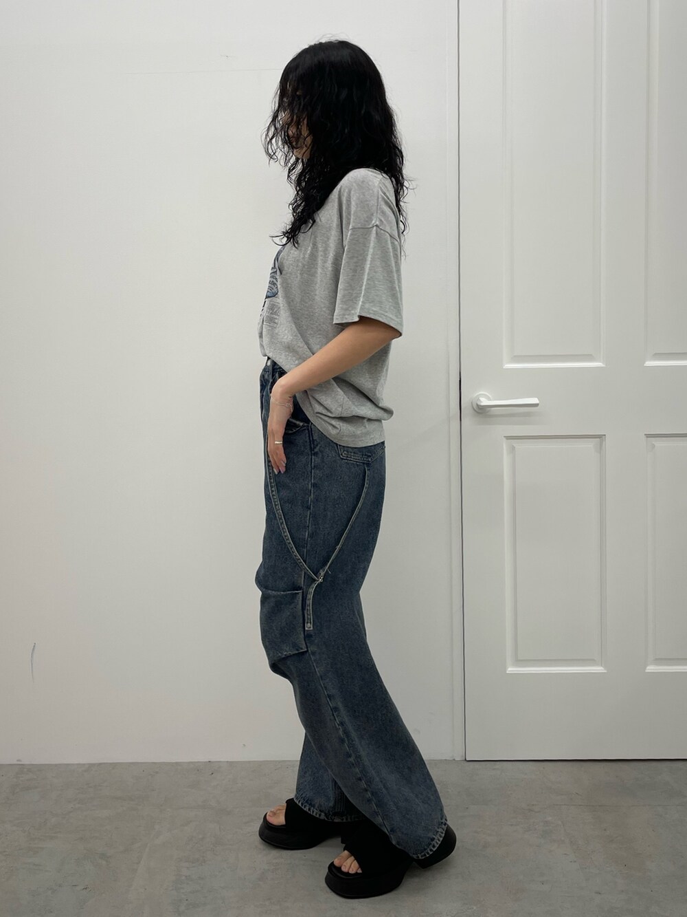 グレー系のTシャツ/カットソー、ブルー系のデニムパンツ、ブラック系のサンダルを着用したレディースの春コーディネートの2枚目の写真