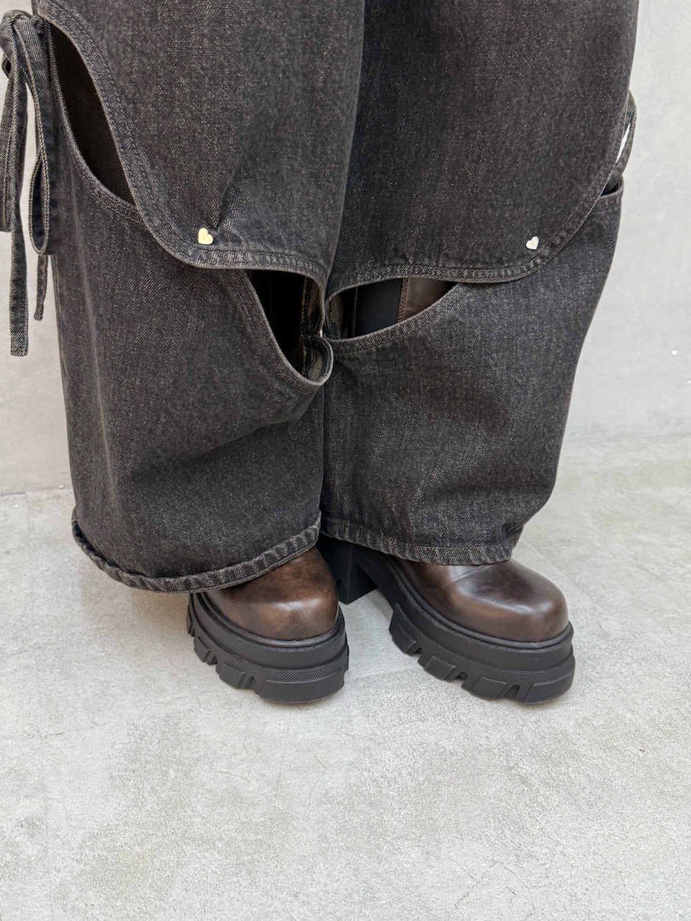 ブラウン系のニット/セーター、ブラック系のデニムパンツ、ブラウン系のブーツを着用したレディースの夏コーディネートの6枚目の写真