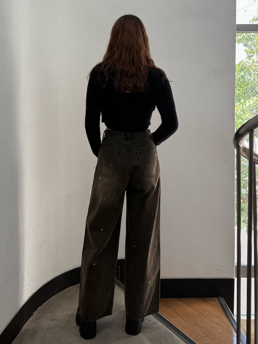 ブラック系のニット/セーター、ブラウン系のデニムパンツ、ブラック系のブーツを着用したレディースの秋コーディネートの3枚目の写真