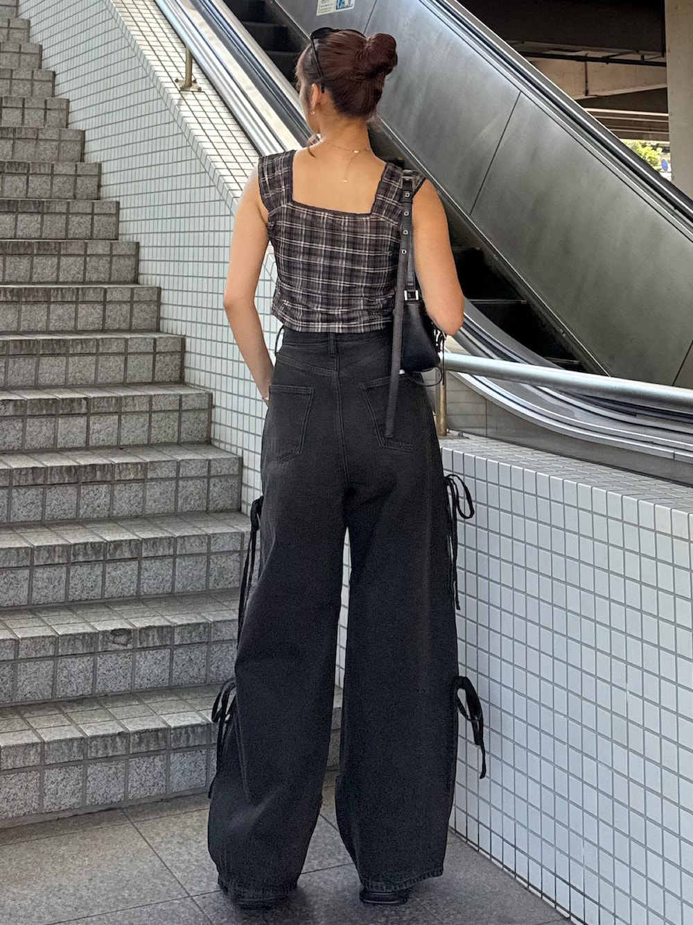 ブラウン系のタンクトップ、ブラック系のハンドバッグ、ブラック系のデニムパンツを着用したレディースの夏コーディネートの3枚目の写真