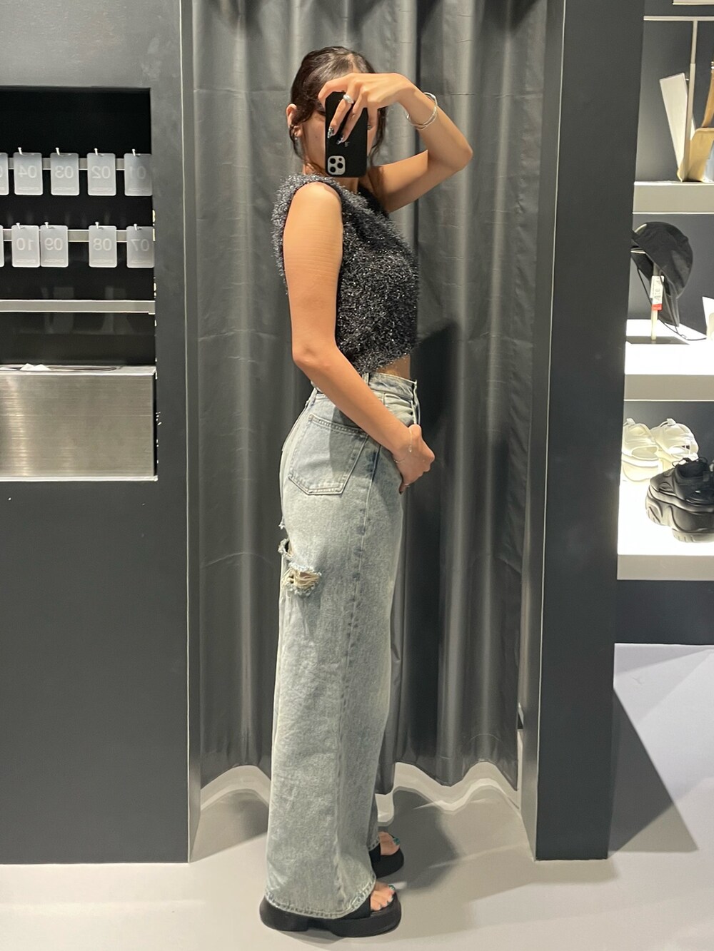 グレー系のタンクトップ、ブルー系のデニムパンツ、ブラック系のサンダルを着用したレディースの夏コーディネートの2枚目の写真