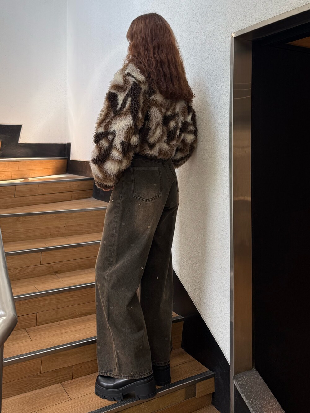 ブラウン系のブルゾン、ブラック系のニット/セーター、ブラウン系のデニムパンツを着用したレディースの秋コーディネートの2枚目の写真