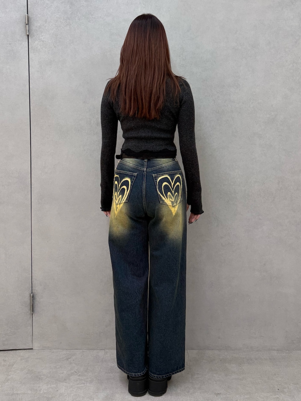 ブラック系のニット/セーター、ブルー系のデニムパンツ、ブラック系のブーツを着用したレディースの冬コーディネートの3枚目の写真