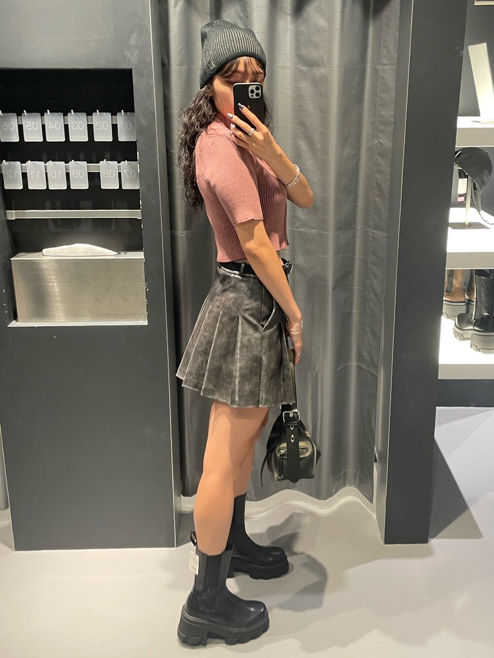 ピンク系のニット/セーター、グレー系のスカート、ブラック系のハンドバッグを着用したレディースの夏コーディネートの2枚目の写真