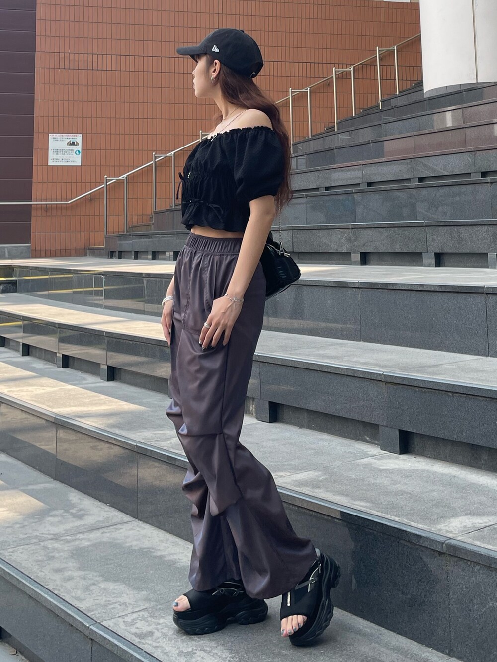 ブラック系のハンドバッグ、ブラック系のTシャツ/カットソー、ブラウン系のその他パンツを着用したレディースの春コーディネートの2枚目の写真