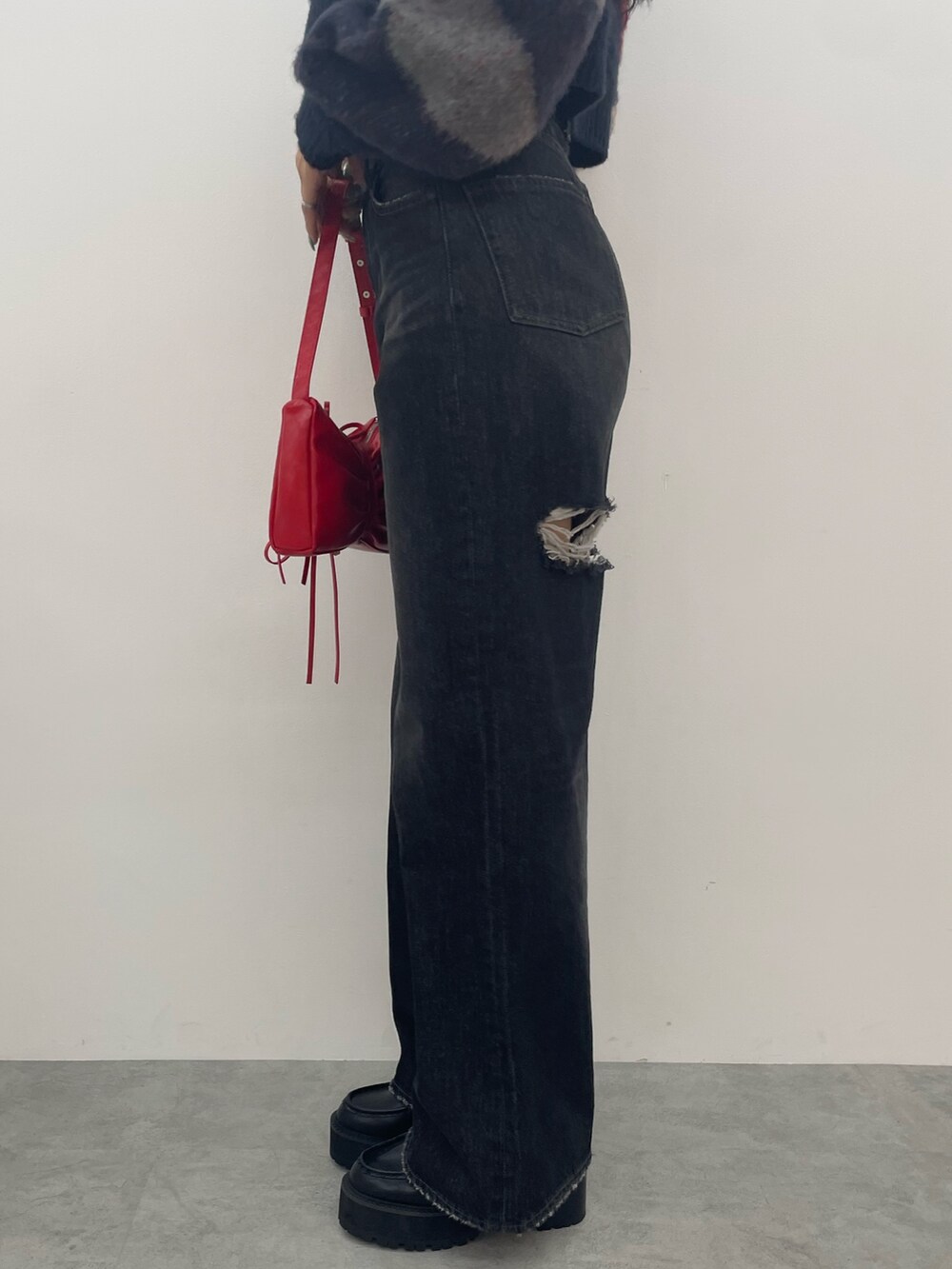 ブラック系のワンピース、ブラック系のデニムパンツ、ブラック系のブーツを着用したレディースの秋コーディネートの7枚目の写真