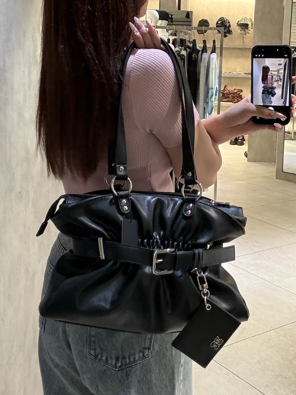 ピンク系のニット/セーター、ブラック系のトートバッグ、ブルー系のデニムパンツを着用したレディースの春コーディネートの5枚目の写真