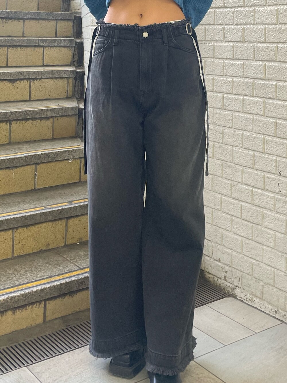 ブルー系のニット/セーター、ブラック系のデニムパンツ、ブラック系のブーツを着用したレディースの春コーディネートの7枚目の写真