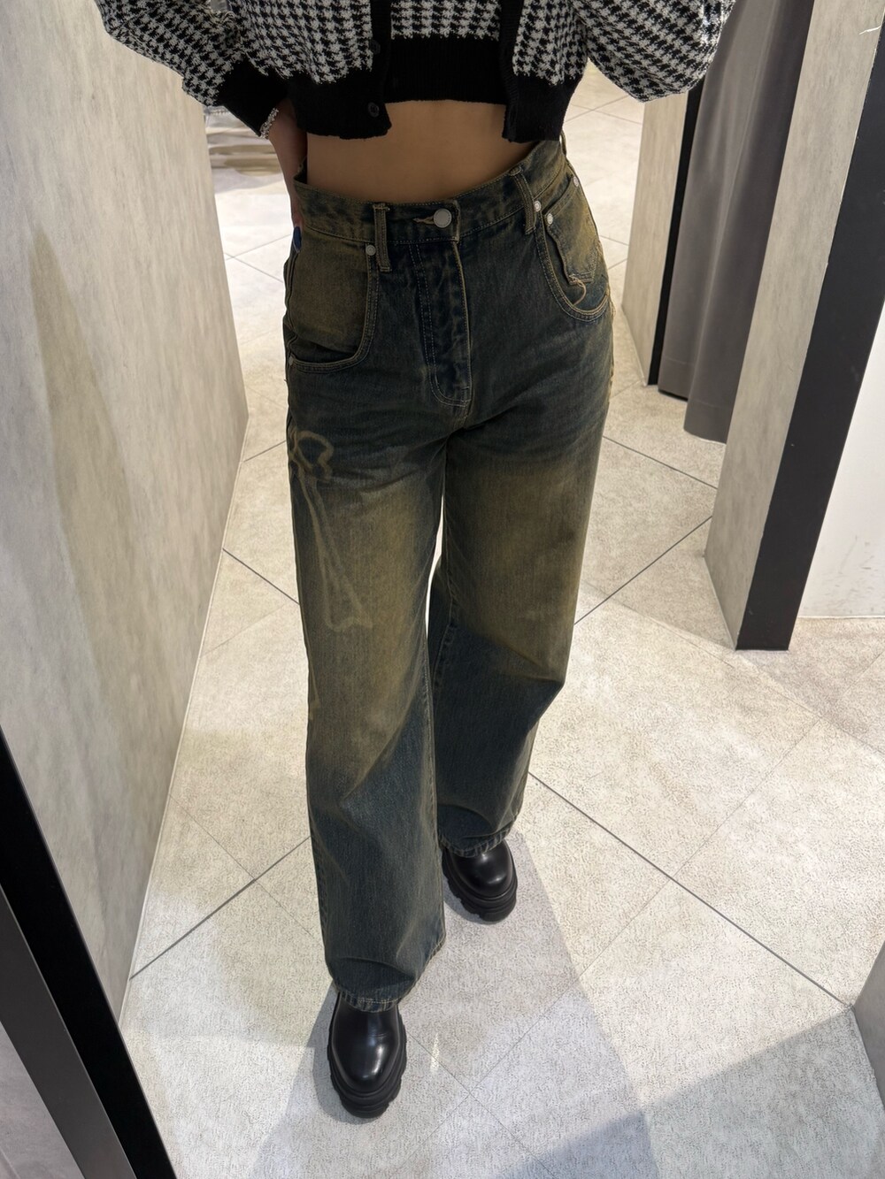 ブラック系のニット/セーター、ブルー系のデニムパンツ、ブラック系のブーツを着用したレディースの秋コーディネートの5枚目の写真