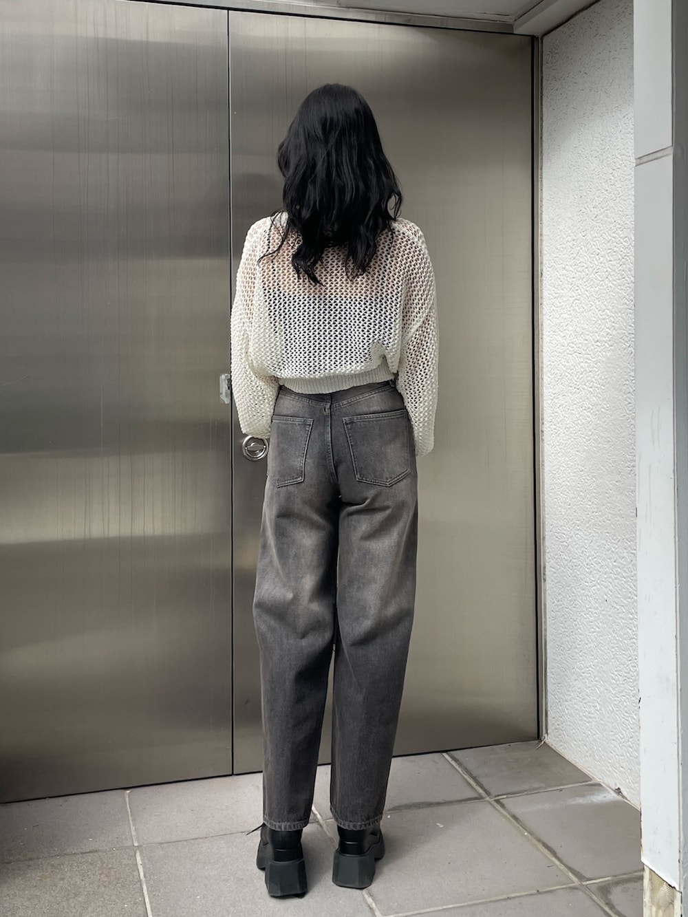 ホワイト系のニット/セーター、ブラック系のキャミソール、グレー系のデニムパンツを着用したレディースの春コーディネートの3枚目の写真