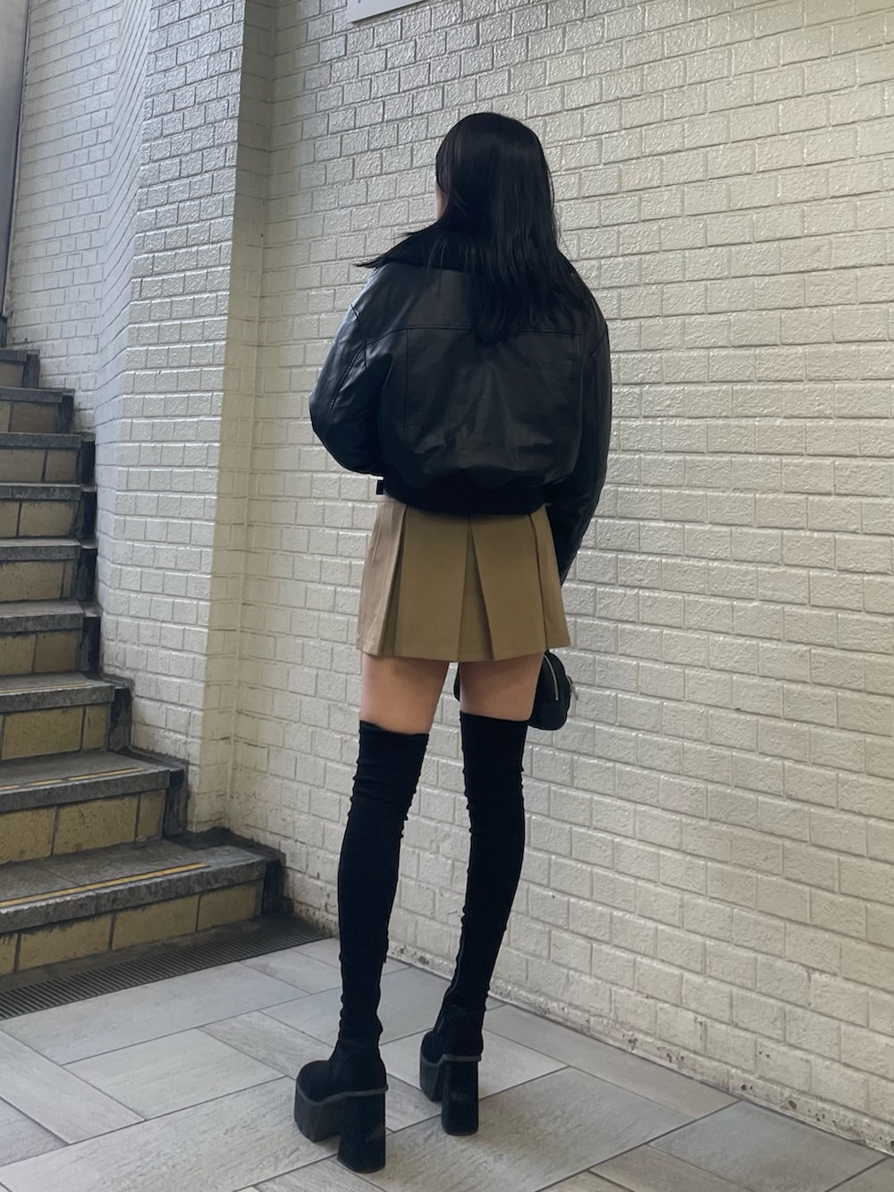 ブラック系のニット/セーター、ブラック系のブルゾン、ベージュ系のスカートを着用したレディースの秋コーディネートの3枚目の写真