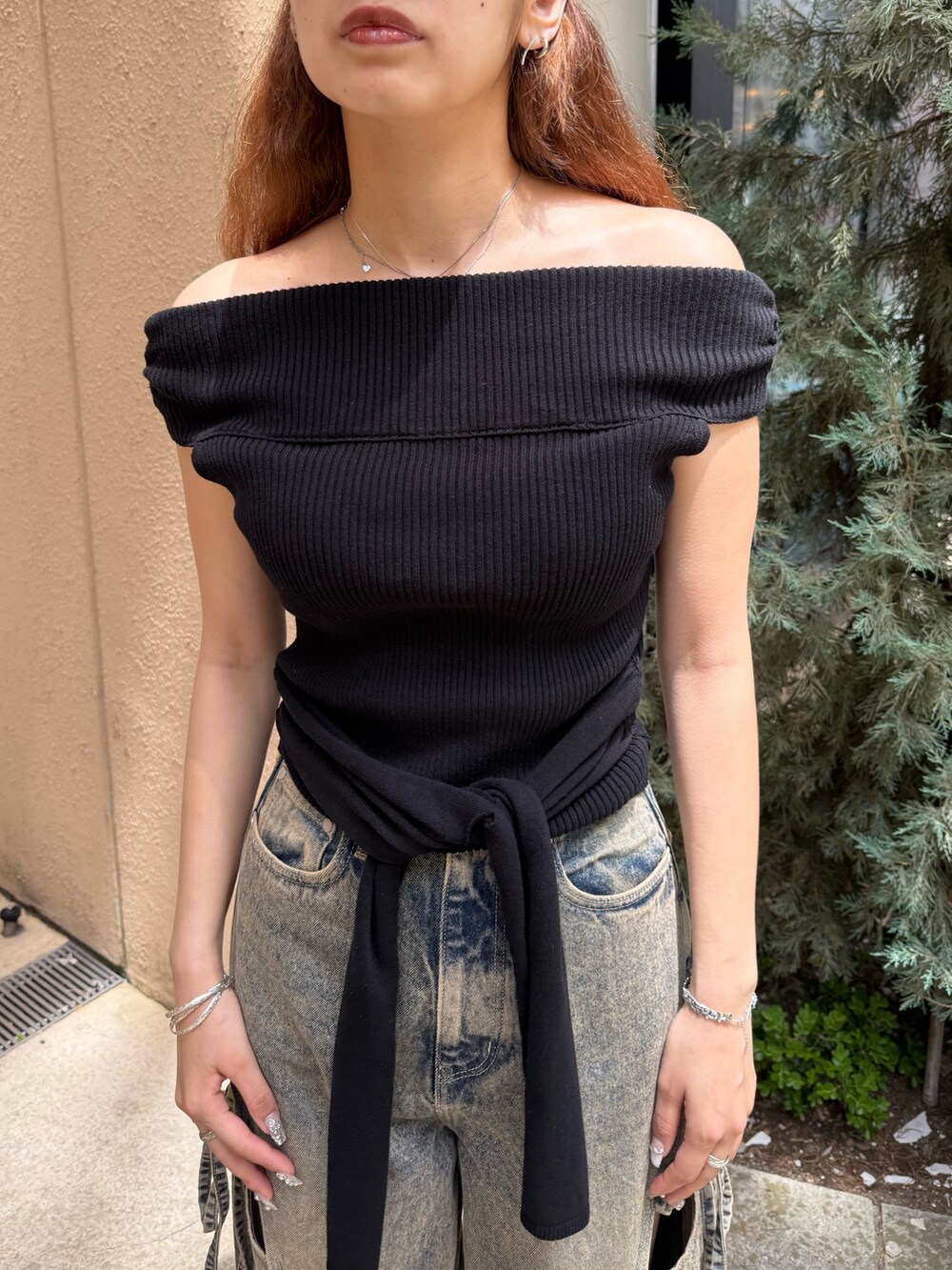 ブラック系のニット/セーター、ブルー系のデニムパンツ、ブラック系のサンダルを着用したレディースの夏コーディネートの4枚目の写真