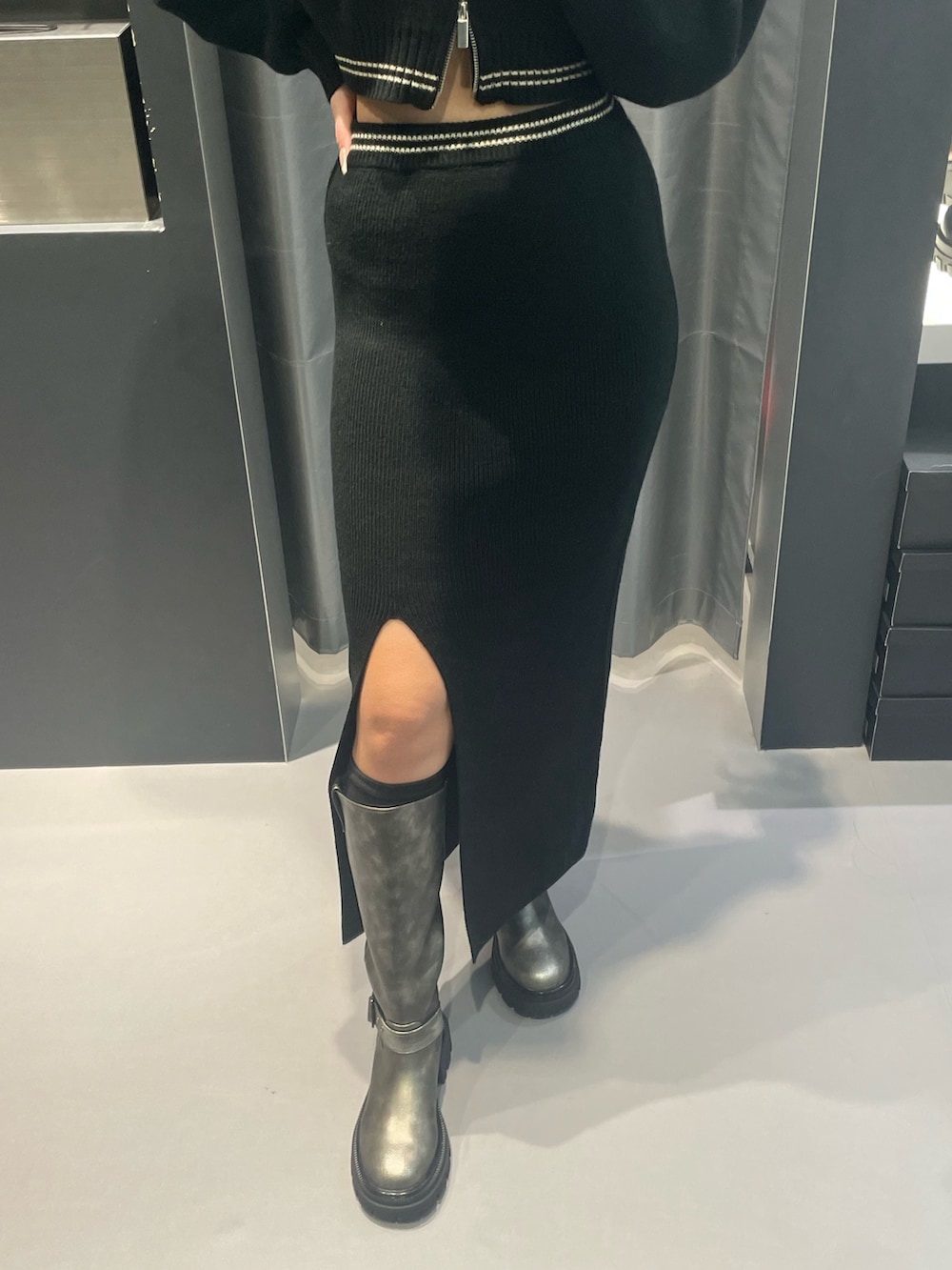 ブラック系のニット/セーター、ブラック系のスカート、シルバー系のブーツを着用したレディースの冬コーディネートの7枚目の写真