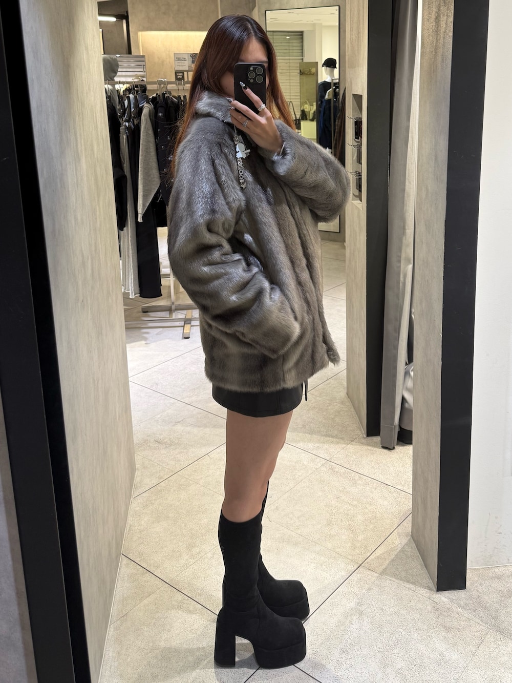 グレー系のその他アウター、ブラック系のスカート、ブラック系のブーツを着用したレディースの秋コーディネートの2枚目の写真