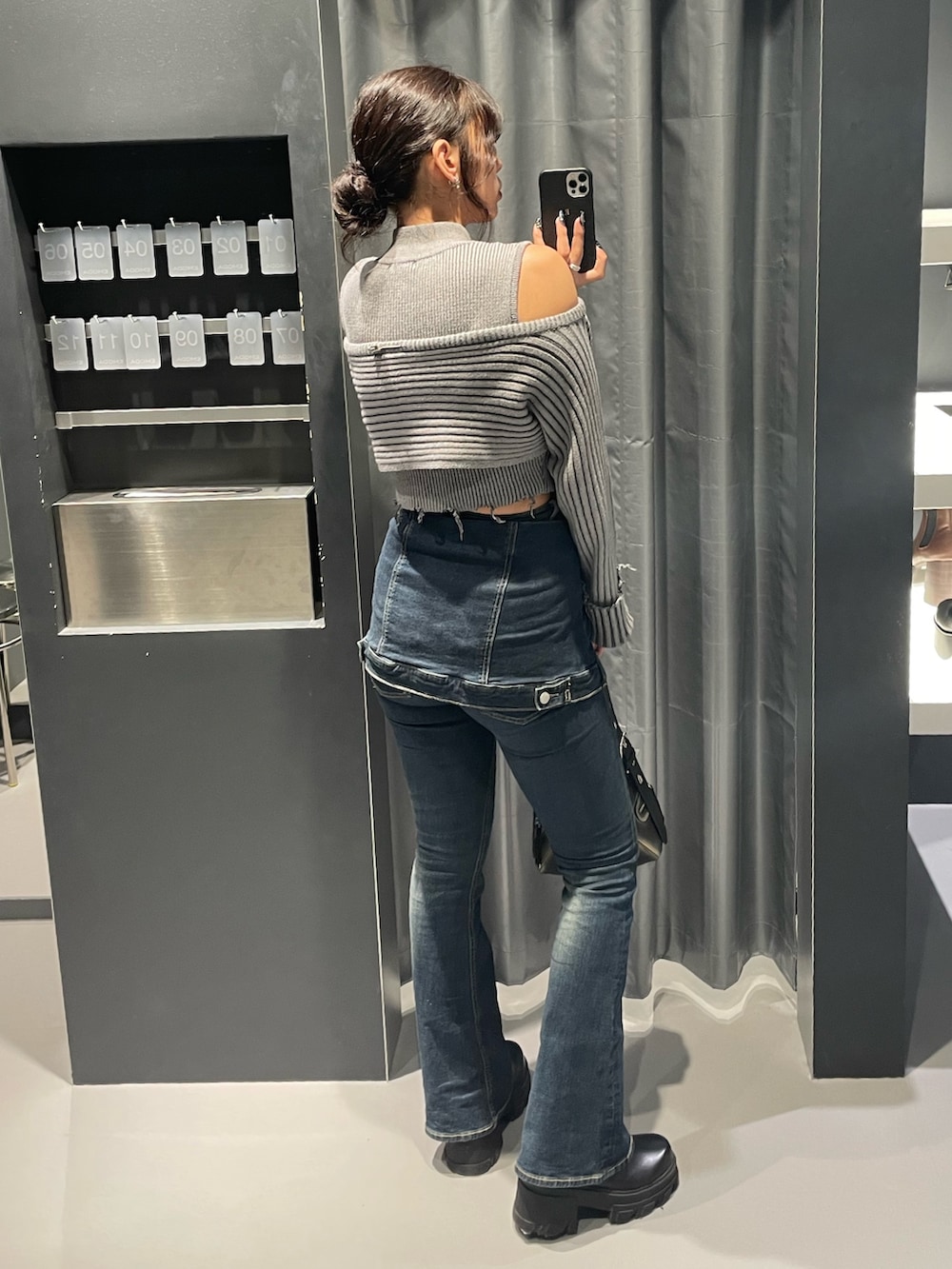 グレー系のニット/セーター、ブルー系のデニムパンツ、ブラック系のハンドバッグを着用したレディースの秋コーディネートの3枚目の写真