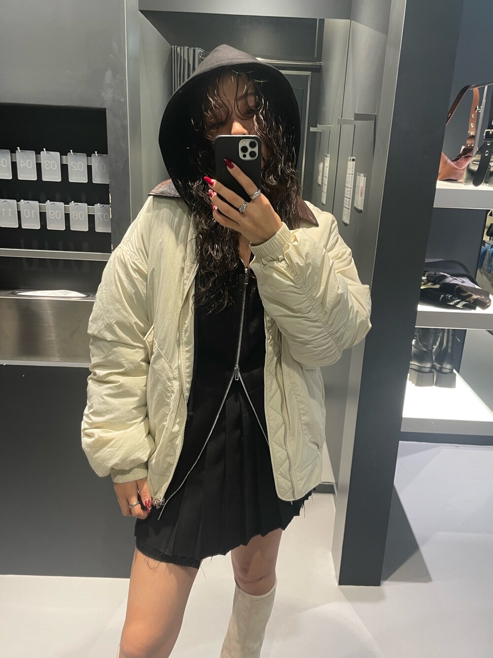 ブラック系のパーカー、ホワイト系のブルゾン、ブラック系のスカートを着用したレディースの秋コーディネートの4枚目の写真