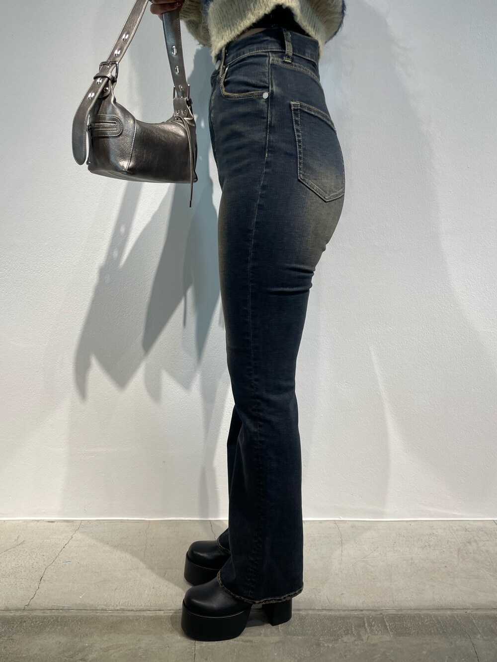 ブルー系のニット/セーター、ブルー系のデニムパンツ、シルバー系のハンドバッグを着用したレディースの秋コーディネートの8枚目の写真