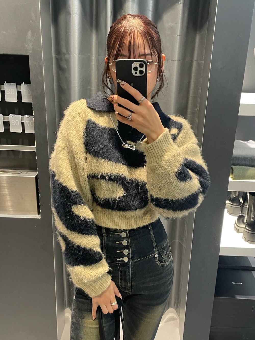 ブルー系のニット/セーター、ブルー系のデニムパンツ、ブラック系のショルダーバッグを着用したレディースの冬コーディネートの4枚目の写真