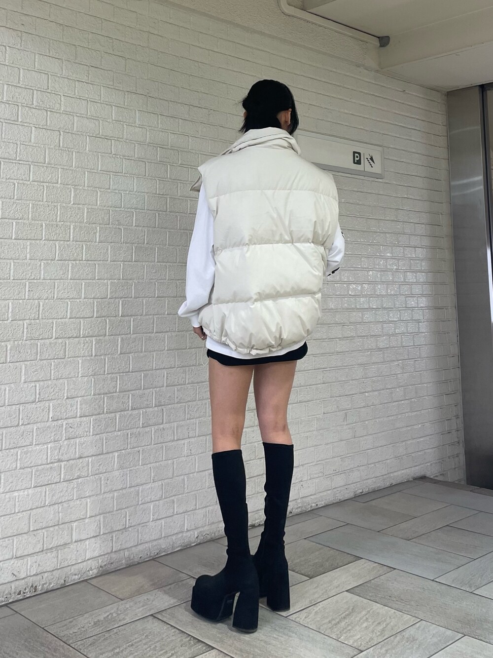 ホワイト系のTシャツ/カットソー、ホワイト系のダウンベスト、ブラック系のスカートを着用したレディースの秋コーディネートの3枚目の写真