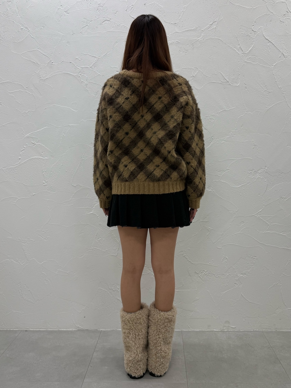 ベージュ系のニット/セーター、ブラック系のスカート、ホワイト系のブーツを着用したレディースの冬コーディネートの3枚目の写真