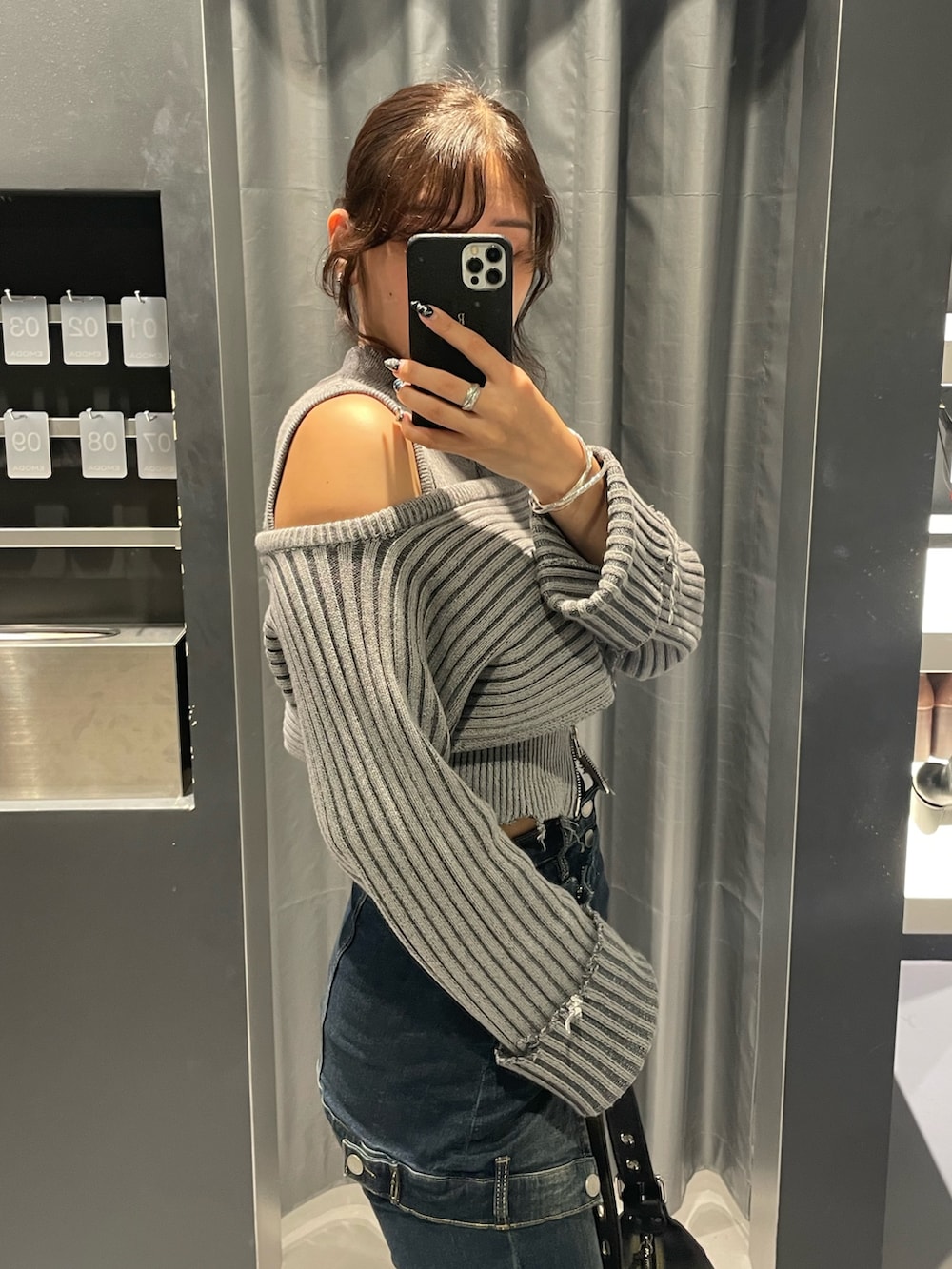 グレー系のニット/セーター、ブルー系のデニムパンツ、ブラック系のハンドバッグを着用したレディースの秋コーディネートの5枚目の写真