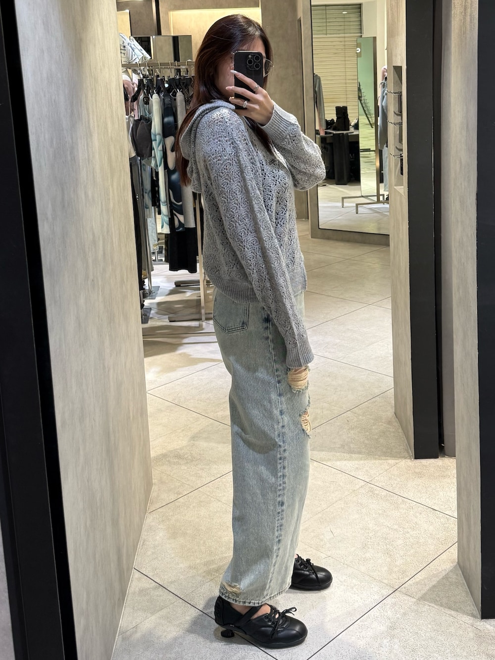 ブラック系のスニーカー、ブルー系のデニムパンツ、グレー系のパーカーを着用したレディースの春コーディネートの2枚目の写真