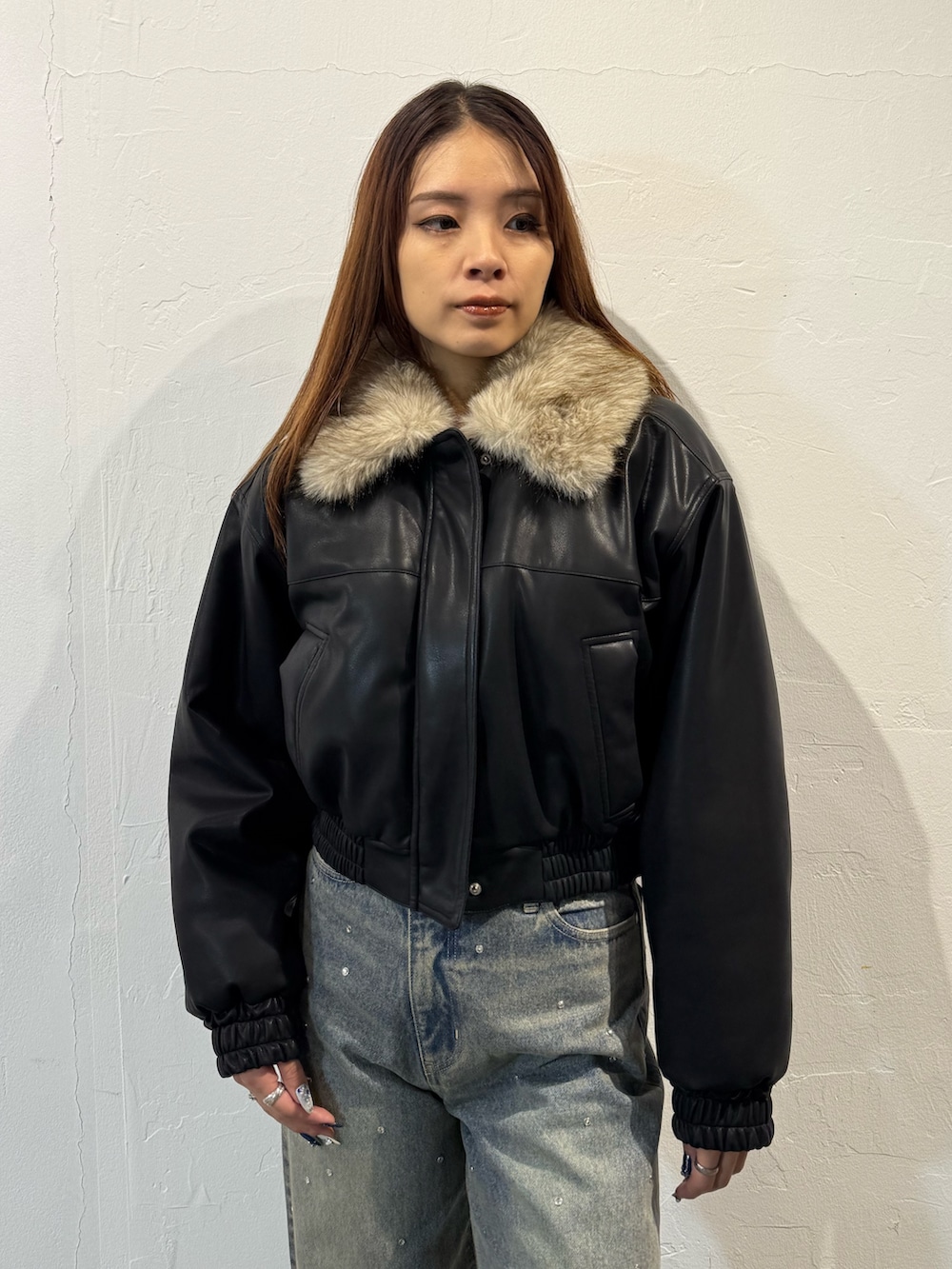 ブラック系のブルゾン、ブルー系のデニムパンツ、ブラック系のブーツを着用したレディースの冬コーディネートの4枚目の写真