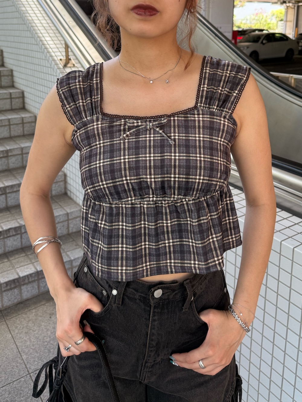 ブラウン系のタンクトップ、ブラック系のハンドバッグ、ブラック系のデニムパンツを着用したレディースの夏コーディネートの4枚目の写真