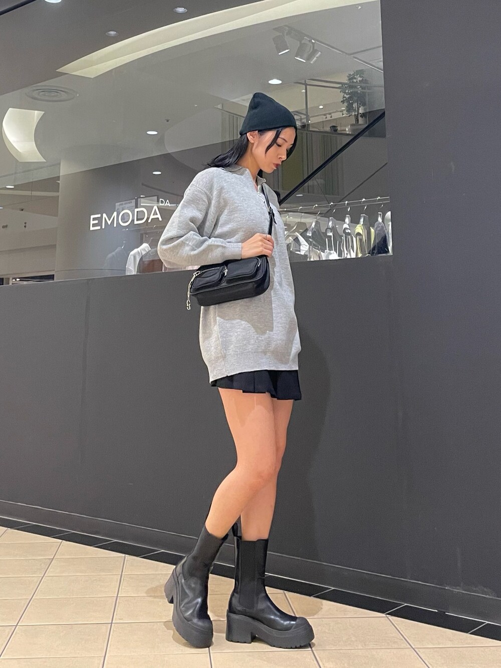 グレー系のワンピース、ブラック系のハンドバッグ、ブラック系のスカートを着用したレディースの秋コーディネートの2枚目の写真